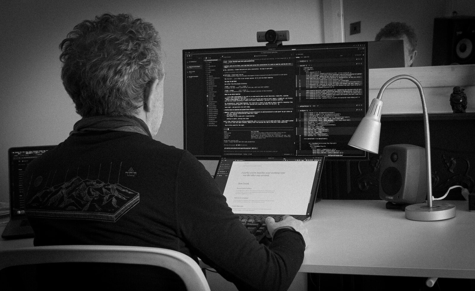 Chris Millwater at his desk reviewing a document with code on screen.